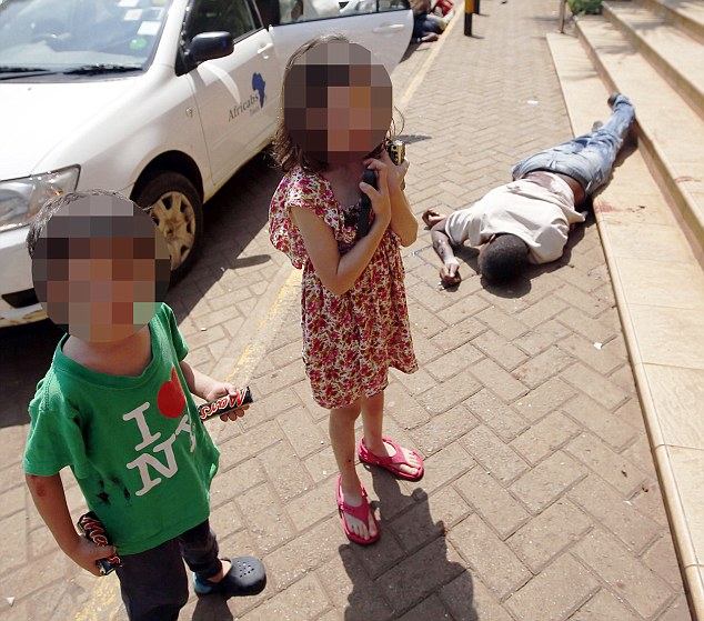 Terrified children wait by the body of a man after escaping from a shopping centre as police search for gunmen in Nairobi